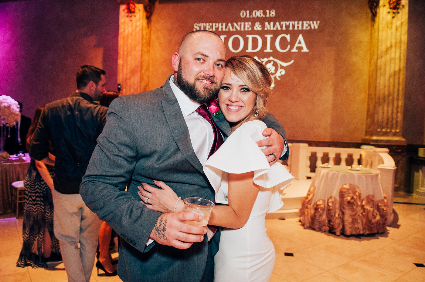 Stephanie and Blake (Brother and Sister) posing together at a wedding reception with a decorated backdrop.